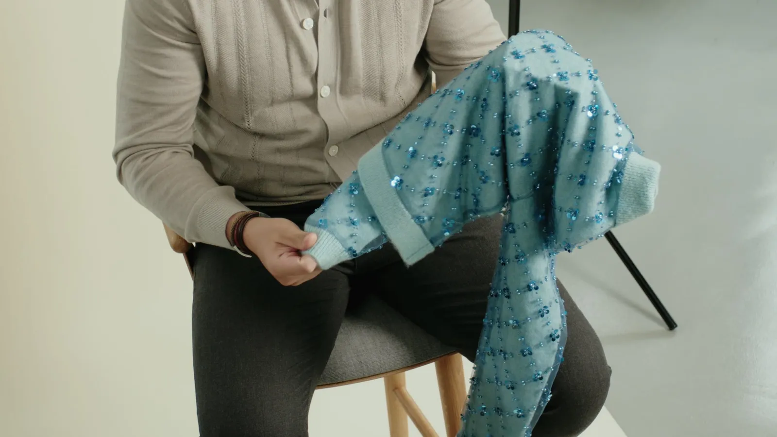 Handheld-Aufnahme: Mitarbeiter hält eine hellblaue Strickjacke mit Pailletten