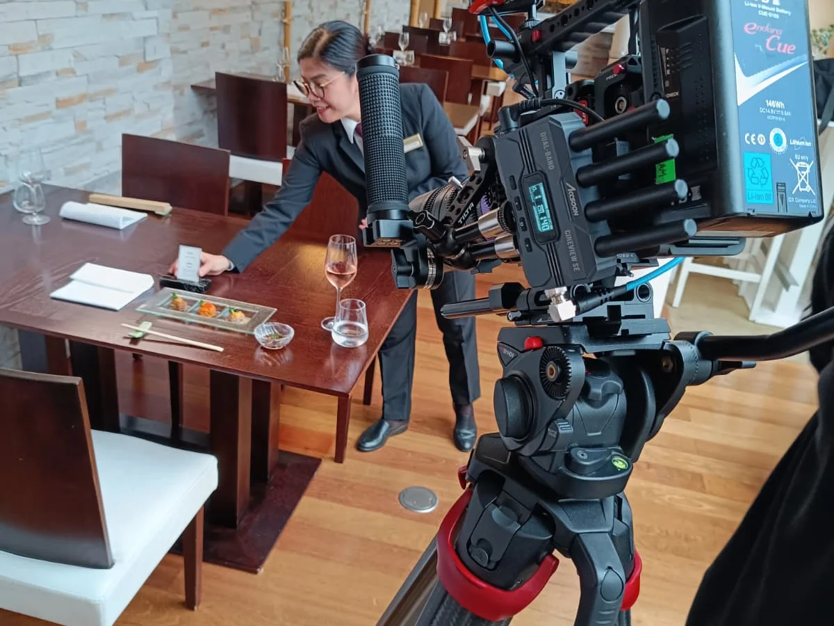 Making-of: Kamera auf dem Stativ filmt eine Servicekraft beim Eindecken