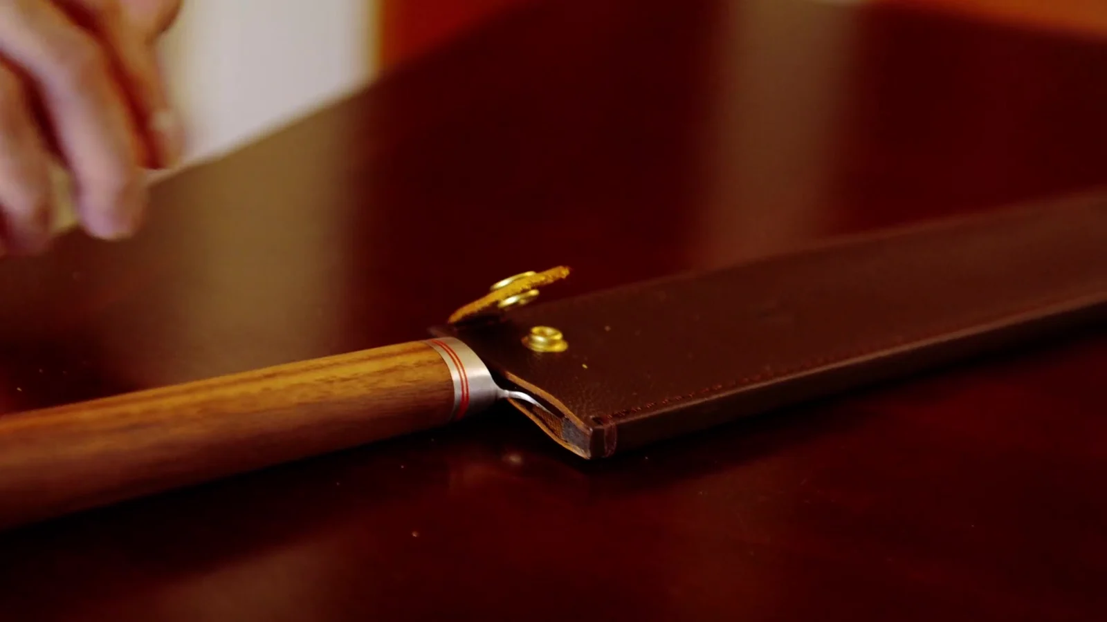 Ein Messer auf dunklem Holz, eine Hand greift danach